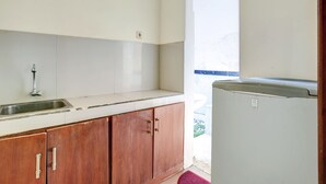 A kitchen with a sink, wooden cabinets, a white countertop, and a refrigerator. - OYO 3902 Pondok 828 Residence (Denpasar)
