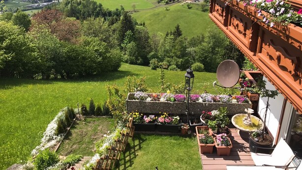 A balcony with a view of a village, a garden with flowers, and a satellite dish. - A wonderful panoramic apartment of 110m2. (Radenthein)