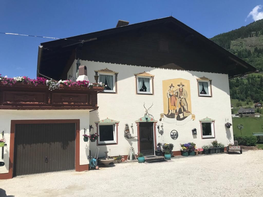 A traditional building with a large mural, a covered porch, and a gravel driveway.