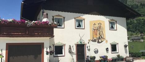 A traditional building with a large mural, a covered porch, and a gravel driveway.