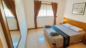 Una habitación de hotel con una cama, una mesita de noche, una lámpara, una ventana con cortinas y un cuadro en la pared.