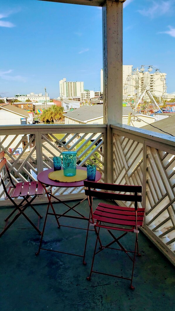 Enjoy the city view from this balcony with a metal railing, a small table, and two chairs.