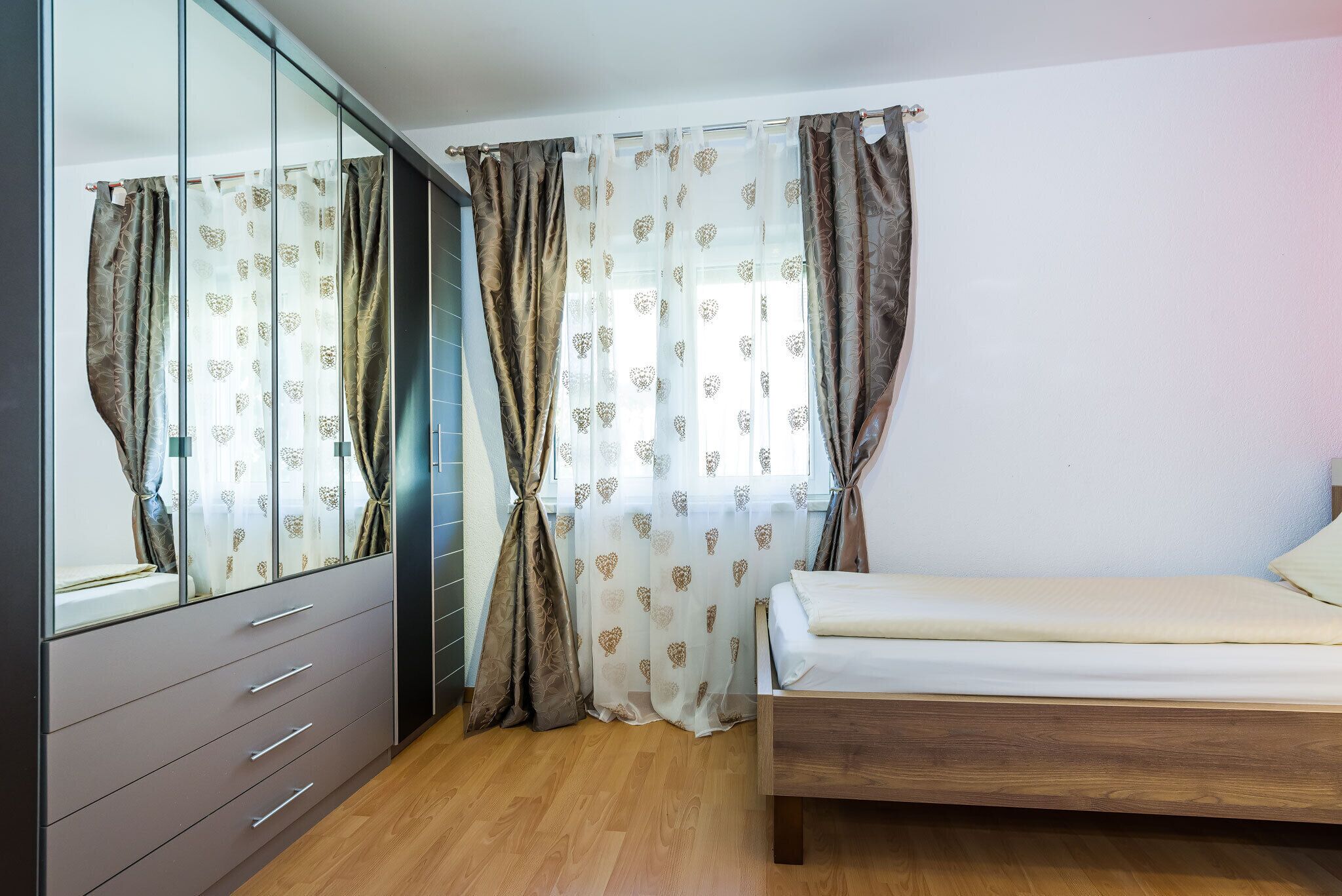 A bedroom with a wooden bed, a wardrobe, and a mirror.