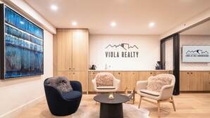 Un interior moderno con un cuadro abstracto grande, dos sillones cómodos, una mesa redonda para café y un aparador de madera.