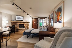 A living room with a fireplace, a television mounted on the wall, and a couch. - Charming Corner Condo, fireplace, spa access, two steps to Vail Village  and  Lifts (Vail)