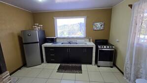 Une cuisine compacte équipée d’un réfrigérateur, d’un four à micro-ondes, d’une cuisinière, d’un évier et de placards.