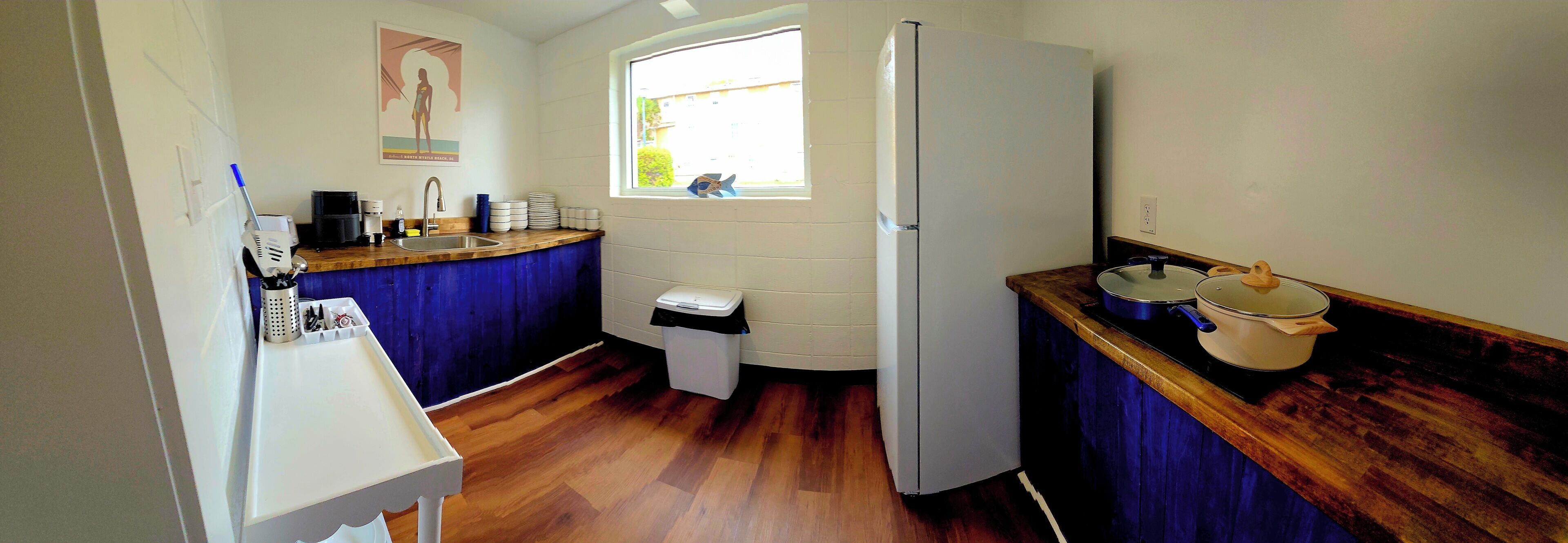 Una cocina compacta con refrigerador, lavamanos y encimera de madera.