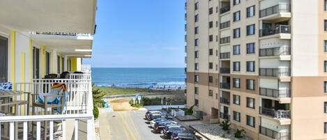 A high-rise building with a balcony overlooking a beach.
