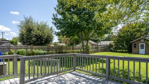 A wooden deck with a white railing, surrounded by a grassy yard and trees. - Mid Peninsula sleeps 8. Feels like home! (Newport News)
