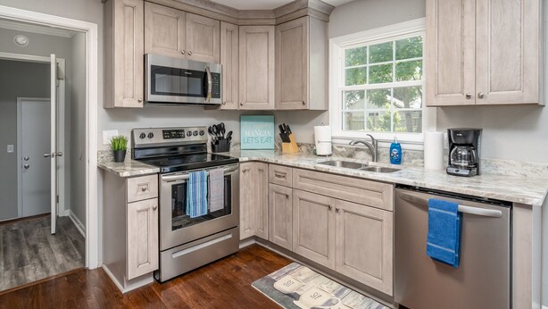 A kitchen with light wood cabinets, stainless steel appliances, a window, and a countertop with various items. - Mid Peninsula sleeps 8. Feels like home! (Newport News)