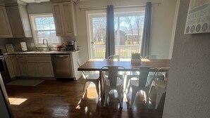 A kitchen with wooden cabinets, a dining table with chairs, a window with curtains, and a view of the outside. - Mid Peninsula sleeps 8. Feels like home! (Newport News)