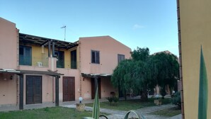 Ein Wohngebäude mit Innenhof, mit einer Pergola, einem Baum und einem gepflegten Rasen.