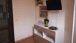Ein Zimmer mit einem Holztv-Schrank, einem an der Wand befestigten Flachbildfernseher und einem Regal mit Dekoration.