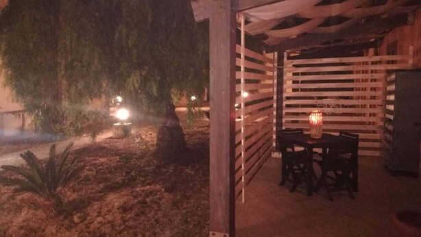 Ein Patio mit Holz-Pergola, einem Tisch mit Stühlen und einer kleinen Feuerstelle.