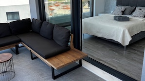 Un dormitorio moderno con una cama grande, un sofá y vistas de la ciudad a través de un ventanal corredero.