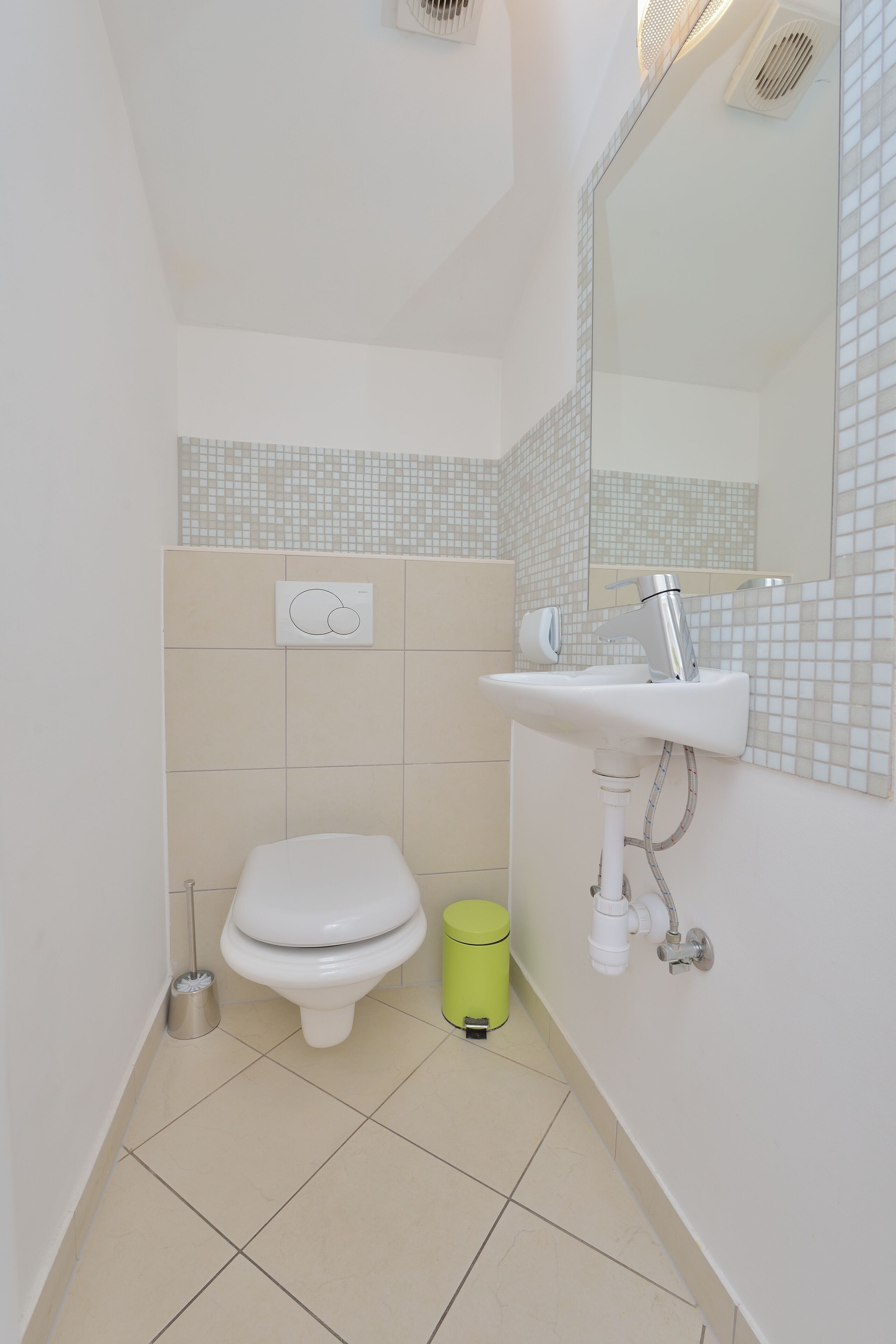 A small bathroom with a toilet, a sink, and a mirror.