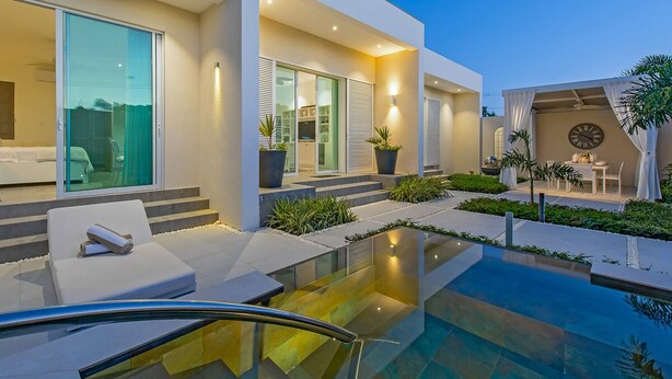 Een modern huis met een zwembad, terras en een klok aan de muur.