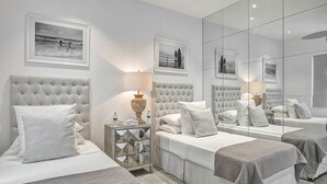 Een hotelkamer met twee bedden, een spiegelwand en beelden in lijsten aan de muur.