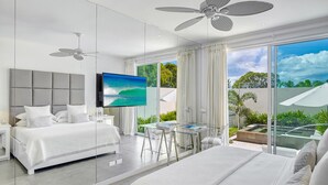 Een moderne hotelkamer met een groot bed, een bureau en een balkon met uitzicht op groen.