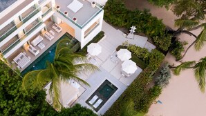 Ein modernes Hotel mit Pool auf dem Dach, Sitzgelegenheiten im Freien und üppiger Bepflanzung.
