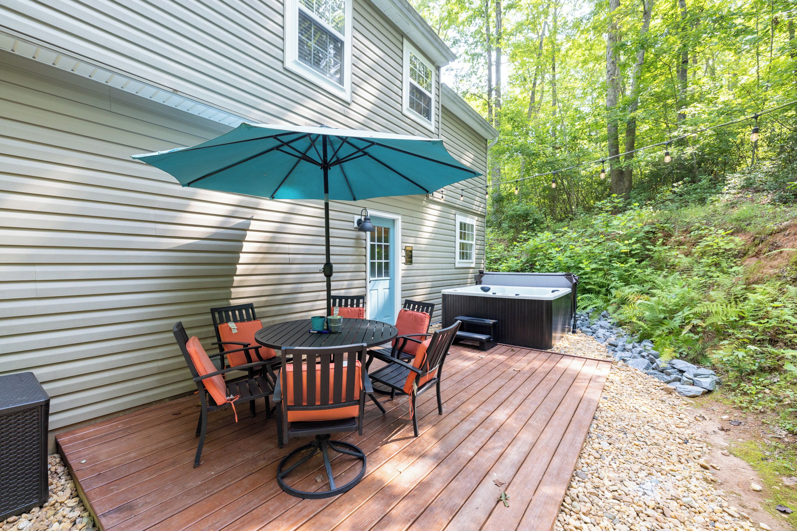 A wooden deck with a table and chairs, a patio umbrella, and a hot tub.