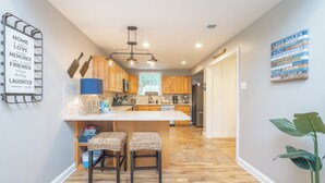 Una cocina moderna con armarios de madera, una isla central con taburetes de bar y una lámpara colgante.