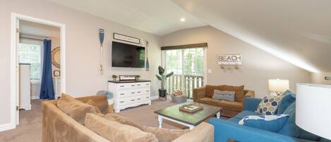 A living room with beige and blue sofas, a television, a coffee table, and a sign that says "BEACH".