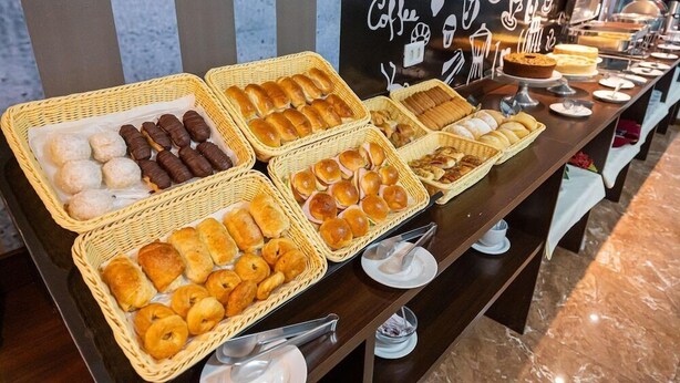 Un bufé con diversas opciones de panadería, incluyendo pasteles, pan y bollos.