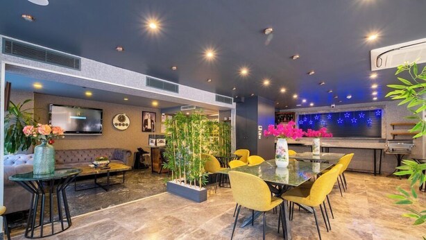 Un hall d’hôtel moderne comprenant un espace repas, des coins salon et un comptoir d’accueil.