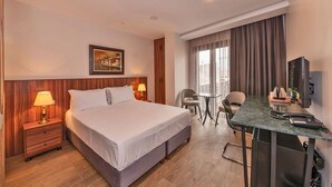 Une chambre d’hôtel comprenant un lit, des lampes de chevet, un bureau avec une chaise, une télévision et une fenêtre avec des rideaux.