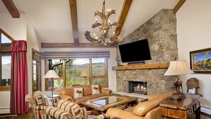 A cozy living room with a stone fireplace, leather sofas, and a television mounted on the wall.