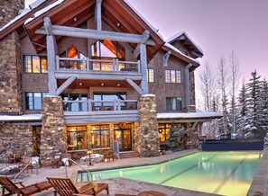 Un gran lodge con piscina, fachada de piedra y varios balcones.