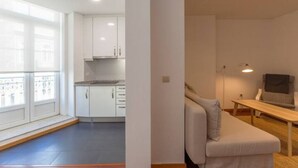 Un apartamento moderno con cocina, zona de estar con sofá y mesa, y balcón con vistas.
