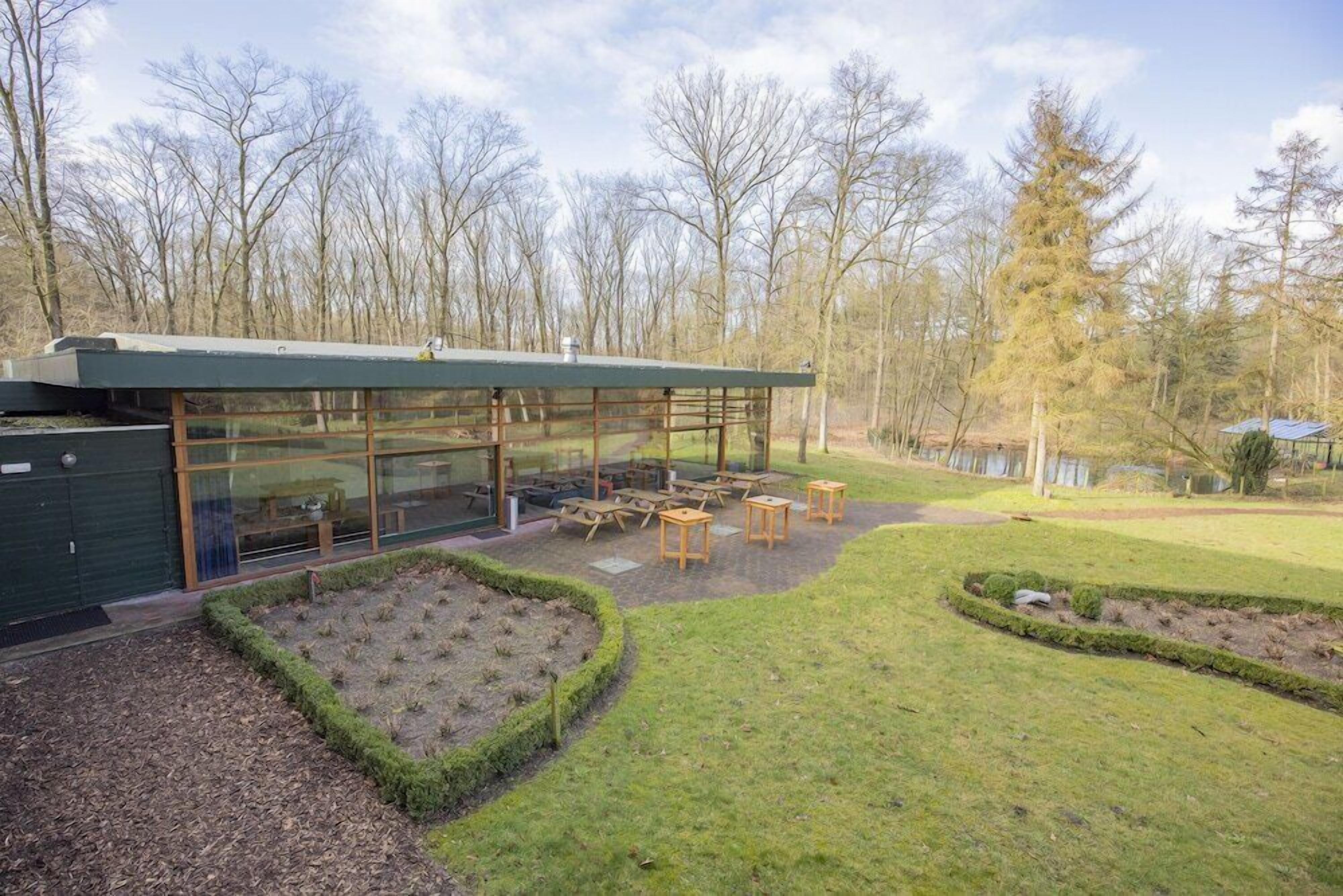 A modern building with large glass windows, outdoor seating area, and a well-maintained garden.