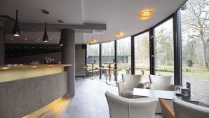 Een modern interieur met een gebogen plafond, een bar en zitplaatsen met grote ramen die uitzicht bieden op het omliggende landschap.