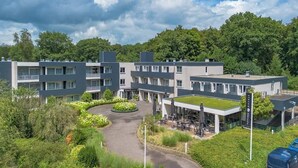 Een modern hotel met meerdere verdiepingen, een centrale binnentuin met groen en een dakterras.
