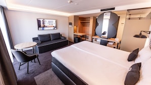 A modern hotel room with a large bed, a sofa, a desk, and a small table. - Gr8 Hotel Sevenum (Sevenum)