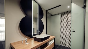 A modern bathroom with a wooden vanity, a large mirror, and a patterned shower wall. - Gr8 Hotel Sevenum (Sevenum)