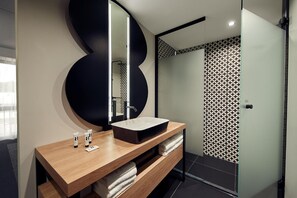 A modern bathroom with a wooden vanity, a large mirror, and a patterned shower wall. - Gr8 Hotel Sevenum (Sevenum)