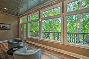 A spacious room with large windows, a fireplace, and a view of the outdoors. - Lake Barkley Home: Private Dock, Kayaks, Fire Pit! (Cadiz)