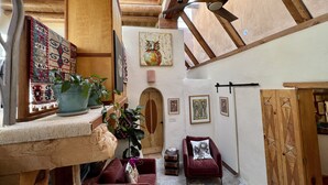 Um interior aconchegante com vigas de madeira, uma porta de madeira e uma cadeira vermelha.