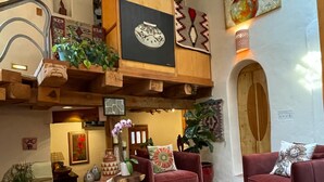 Uma sala de estar aconchegante com lareira, poltronas vermelhas, mesa de centro de madeira e um tapete estampado.
