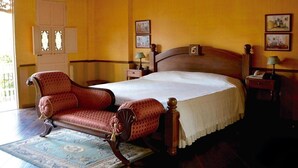 Un dormitorio tradicional con cama de madera, un sillón antiguo y un armario de madera.