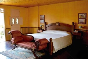 Un dormitorio tradicional con cama de madera, un sillón antiguo y un armario de madera.