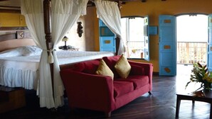 Un dormitorio con una cama con dosel, un sofá rojo y un dosel.