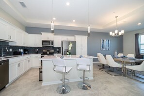 A modern kitchen with white cabinets, stainless steel appliances, and a central island with bar stools. - IL405 Storey Lake Condo 2 bed 2 bath  Free Waterpark (Kissimmee)