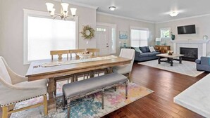 A spacious living room with a dining area, a fireplace, and a television mounted on the wall. - Family home downtown CDA walk to lake and dining (Coeur d'Alene)