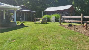 Enjoy al fresco dining in a serene natural setting surrounded by lush greenery and a beautifully maintained lawn.