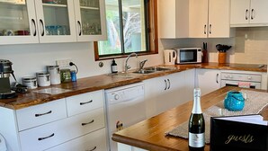 Una cocina moderna con armarios blancos, encimera de madera, lavavajillas integrado y ventana con vistas a zonas verdes.