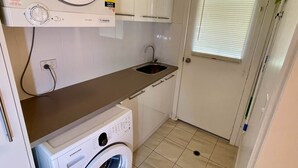 Un lavadero pequeño equipado con lavadora, secadora, lavamanos y una puerta con ventana.